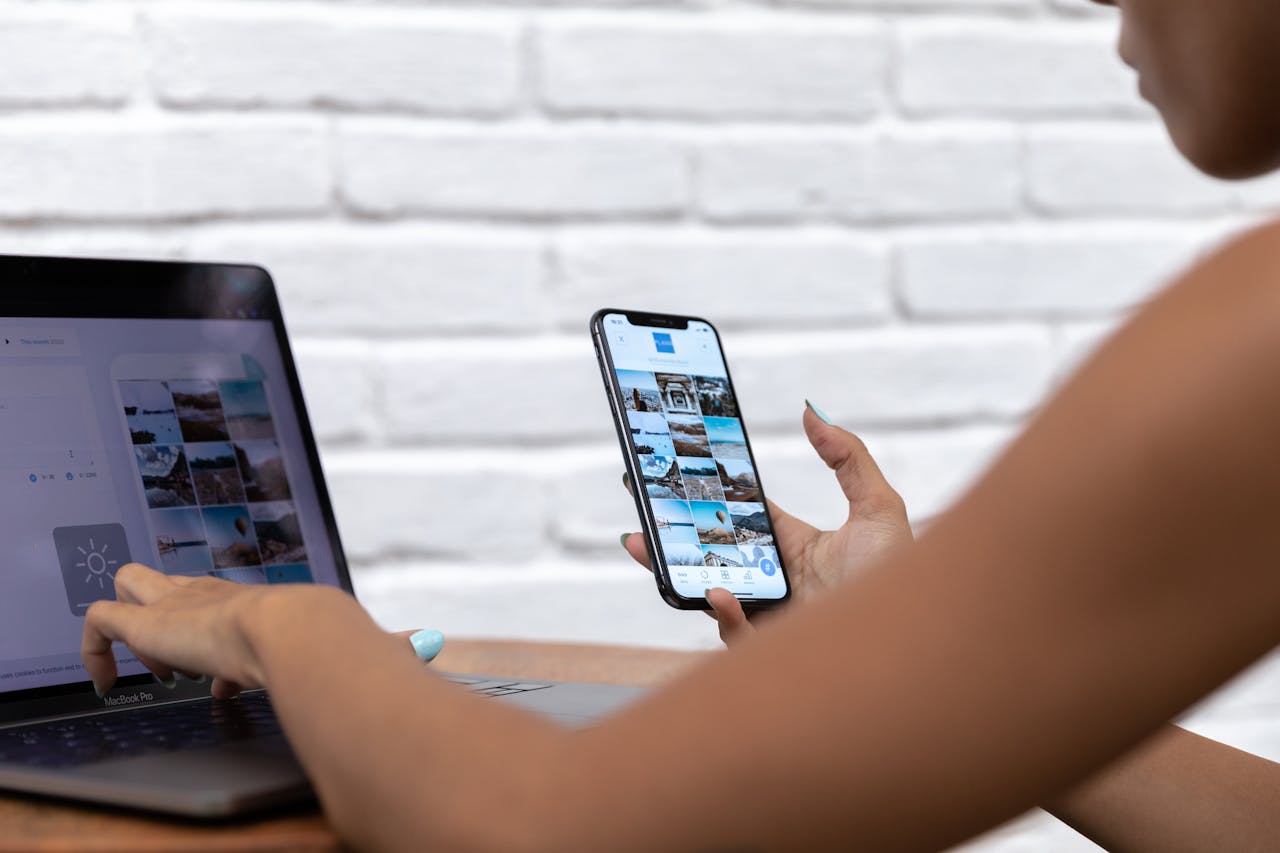 A woman working remotely using a laptop and smartphone, focusing on social media content.